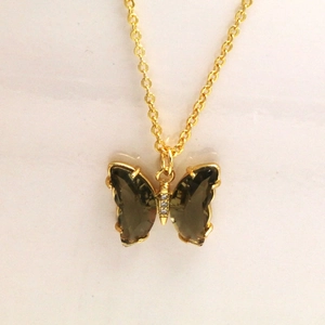 Gros plan détaillé du pendentif papillon doré avec des ailes en cristal vert brillant