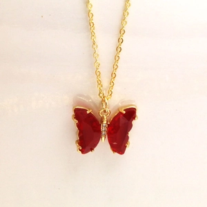 Vue détaillée d'un pendentif papillon en cristal rouge avec zircons sur chaîne dorée
