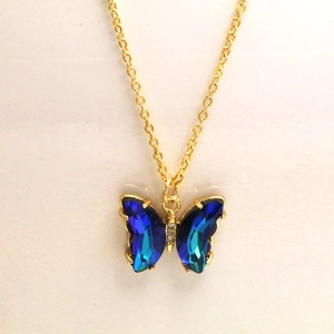 Gros plan du pendentif papillon doré avec cristaux bleus facettés et détails en zircon