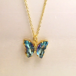 Vue macro du pendentif papillon avec cristaux dégradés bleus et chaîne en métal doré