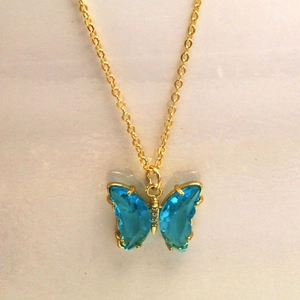 Détail macro du collier papillon avec ailes en cristal bleu et chaîne dorée