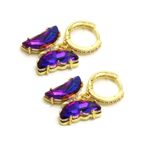 Détail de boucles d'oreilles papillon dorées avec cristaux dégradés violets et zircons