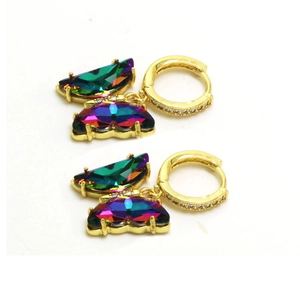 Détail de créoles dorées avec pendentifs papillon en cristal coloré et pierres de zircon