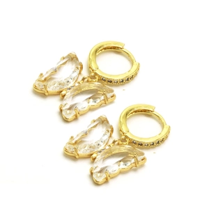 Détail de boucles d'oreilles créoles papillon dorées avec cristaux facettés et zircons