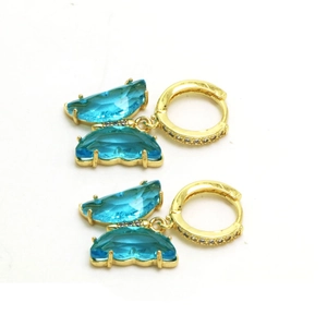 Gros plan de boucles d'oreilles papillon en cristal bleu ciel avec anneaux dorés