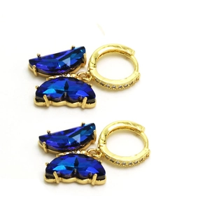 Détail de boucles d'oreilles papillon en cristal bleu avec plaqué or et zircons blancs