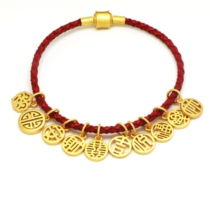 Macro detail of red braided bracelet featuring gold-toned lucky Chinese character charms