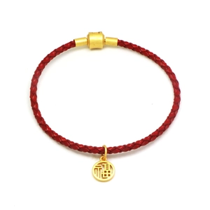 Detailed close-up of a red woven bracelet featuring a gold hollowed Fu character pendant
