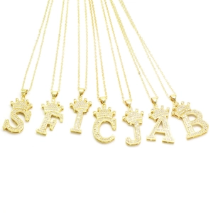 Gold crown letter necklaces set with sparkling zircon pavé pendants on white base