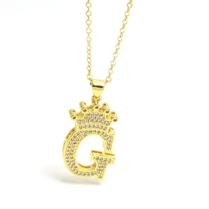 Macro shot of gold letter G pendant with crown design and shimmering zircon stones
