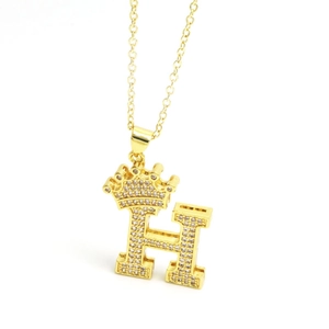 Macro detail of gold crown letter H pendant necklace with sparkling cubic zirconia inlay