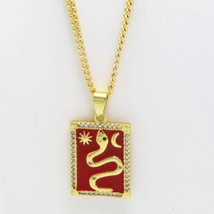 Makroaufnahme von goldenem Tarot-Anhänger mit roter Emaille-Schlange und Kristallen