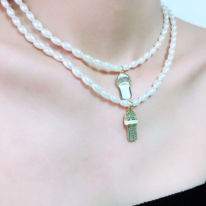 Detail van dubbellaagse parelketting met met diamanten ingelegde slippers als hangers