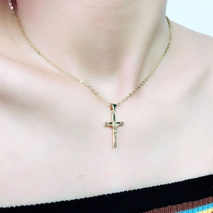 Detailopname van gouden crucifix hanger met Jezusfiguur aan een fijne schakelketting