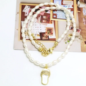 Detail van witte parelketting met gouden slippers-hanger en sprankelende kristallen
