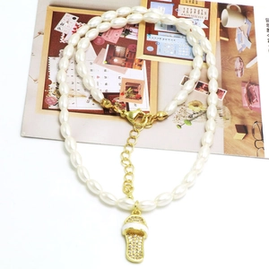 Detail van parelketting met sprankelende sandaal hanger en gouden verstelbare sluiting