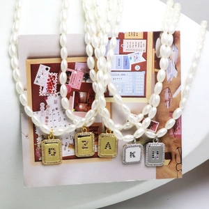 Faux pearl necklace with initial pendants in gold square frames and colorful zircons