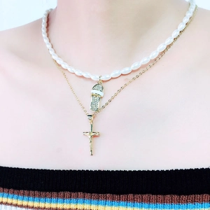 Detail van gelaagde gouden ketting met parels en strass slipper hanger met kruis