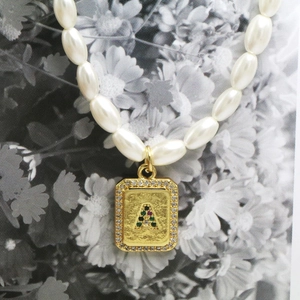Macro shot of rectangular gold letter A pendant with pearls and colorful zircons