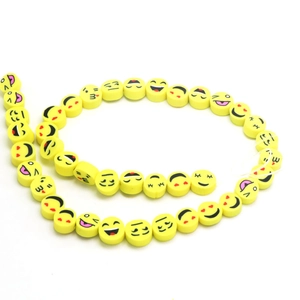 Vibrant yellow smiley face clay beads for DIY jewelry making arranged in a spiral