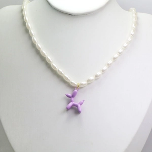 Détail du pendentif chien ballon violet sur un collier de perles blanches élégantes