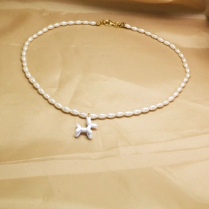 Détail du collier de perles vintage avec un pendentif chien ballon blanc sur tissu en soie
