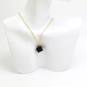Gros plan du collier en chaîne dorée avec pendentif sac à main noir sur un mannequin blanc