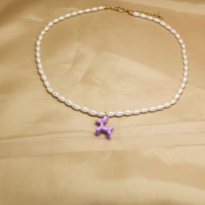 Gros plan d'un collier en perles blanches avec pendentif chien ballon violet vif