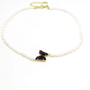 Detalle de collar de perlas con colgante de mariposa de cristal púrpura y cierre dorado