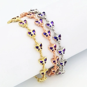 Detailaufnahme der Schmetterlingsarmbänder in Gold, Roségold und Silber mit lila Emaille.