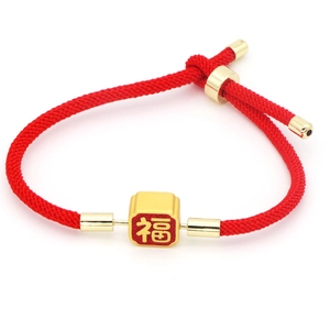 Detailed close-up of handmade red braided cord bracelet with golden Fu character charm
