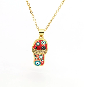 Detail view of gold necklace with red flip-flop pendant featuring blue evil eye charms