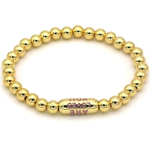Detail view of 18k gold-plated beaded bracelet with You Are Loved engraved cylinder