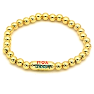 Detailed close-up of 18k gold plated beaded bracelet with colorful engraved text charm