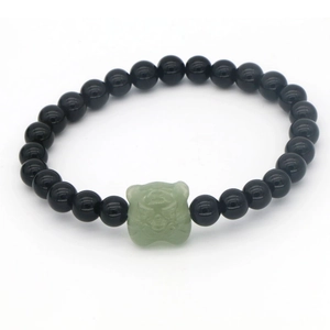 Primer plano de pulsera de obsidiana con un colgante de cabeza de tigre en jade verde
