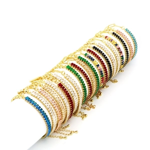 Dettaglio di bracciali dorati con zirconi colorati su supporto espositivo bianco