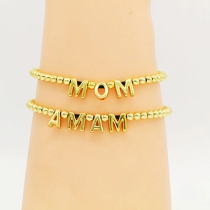 Detail of two golden beaded bracelets featuring MOM and AMAM letter pendants