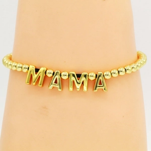 Close-up of golden beaded Mama letter charm bracelet worn on a woman's wrist