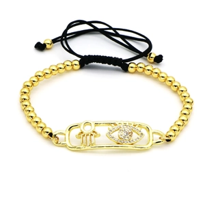 Detalle de pulsera Hamsa y Evil Eye con cordón negro ajustable y cuentas doradas pulidas