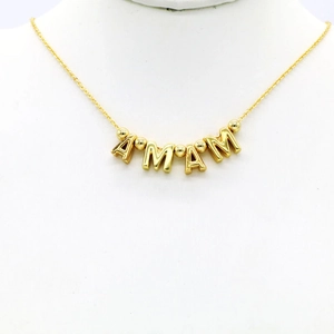 Macro detail of gold-plated Mama letter beads and round spacers on a necklace