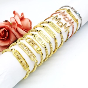 Dettaglio di bracciali con perline dorate con incisioni mama e queen e pietre di zircone