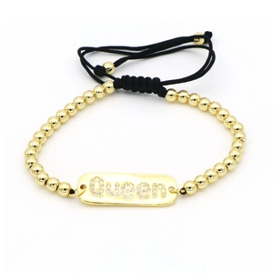 Vista macro dettagliata del bracciale con perle dorate e scritta Queen con strass