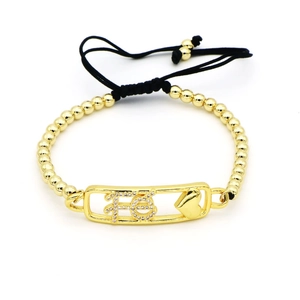 Dettaglio del bracciale dorato a sfere con scritta Fe e un piccolo motivo a cuore