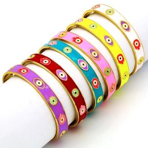 Detailed close-up of colorful enamel evil eye bracelets on a white cylinder stand