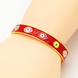 Detail of red enamel evil eye cuff bracelet with multi-color Fatima hand symbols on wrist