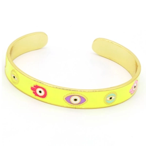Detail showing yellow enamel Hamsa hand and evil eye patterns on a gold cuff bracelet
