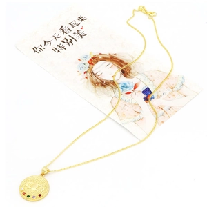 Détail du collier médaille doré avec gravure œil et serti de cinq pierres colorées