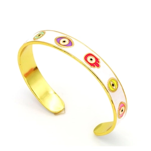 Detail of white enamel cuff bracelet featuring colorful evil eye and Hamsa hand charms