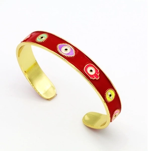 Detail of red enamel cuff bangle with colorful evil eye and Hamsa palm patterns