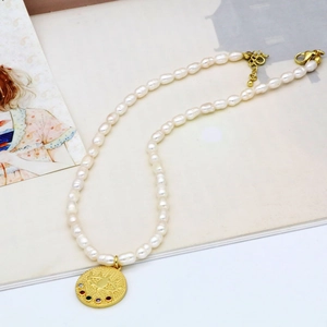 Détail d'un collier de perles baroques avec pendentif œil maléfique doré et gemmes colorées